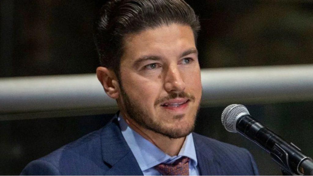 Man in a Navy Suit and Light Blue Shirt Speaks into a Microphone. - Alcaldes Regios