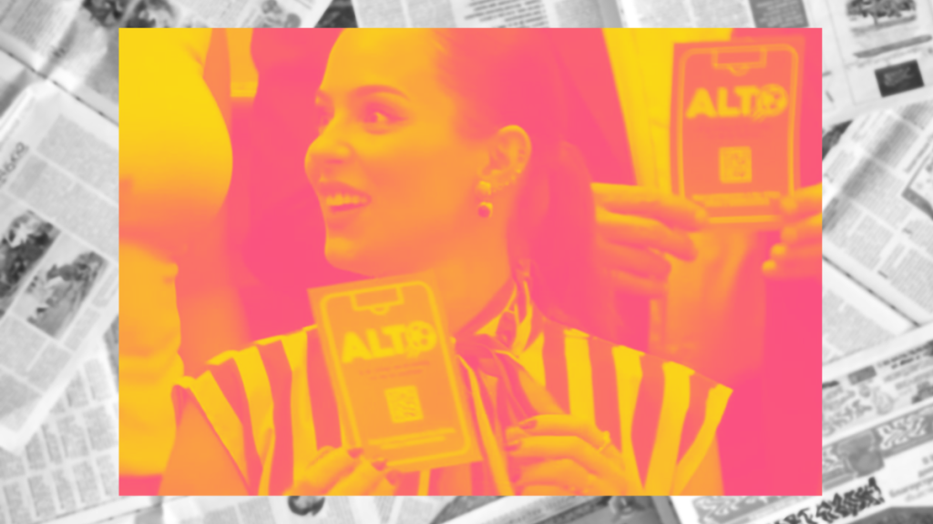 Smiling Woman in a Striped Shirt Holds a Badge Labeled Alt at a Promotional Event. - Alcaldes Regios