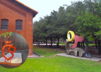 Campus Courtyard: Red Brick Building on the Left, Green Lawn, and Large Abstract Sculptures in the Park. - Alcaldes Regios
